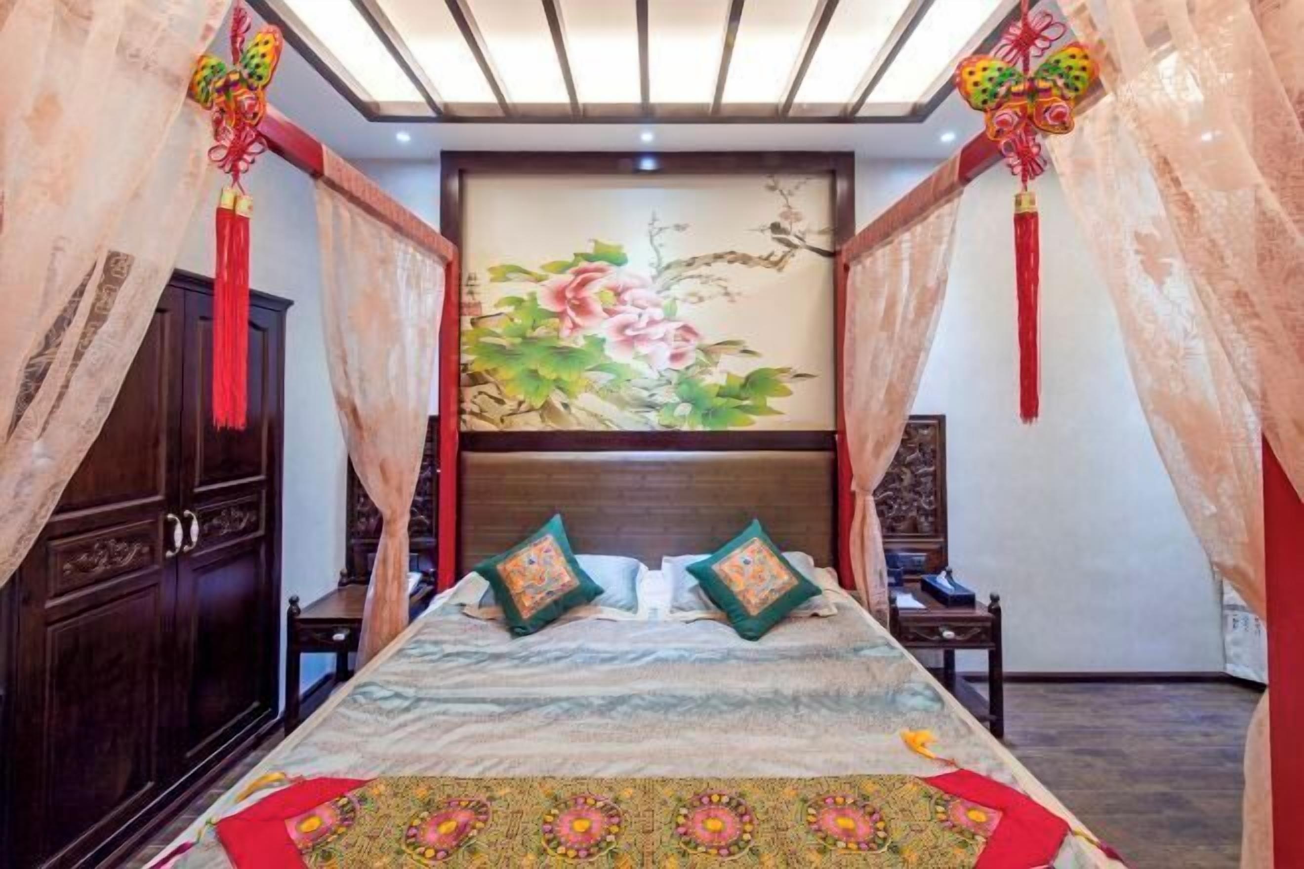 Un dormitorio con cama, cortinas, un cuadro y un armario de madera.