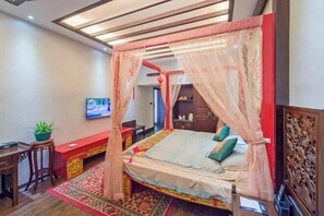 Un dormitorio con cama a dosel, televisión, escritorio y un panel de madera decorativo.