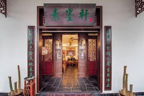 Entrada de un edificio tradicional chino, con un letrero, puertas de madera y piso de baldosas.