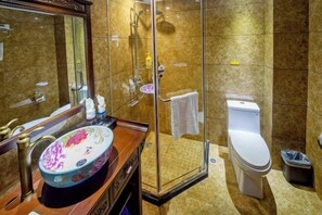 Une salle de bain avec une douche à parois de verre, des toilettes blanches et un meuble-lavabo en bois agrémenté d’un lavabo décoratif.