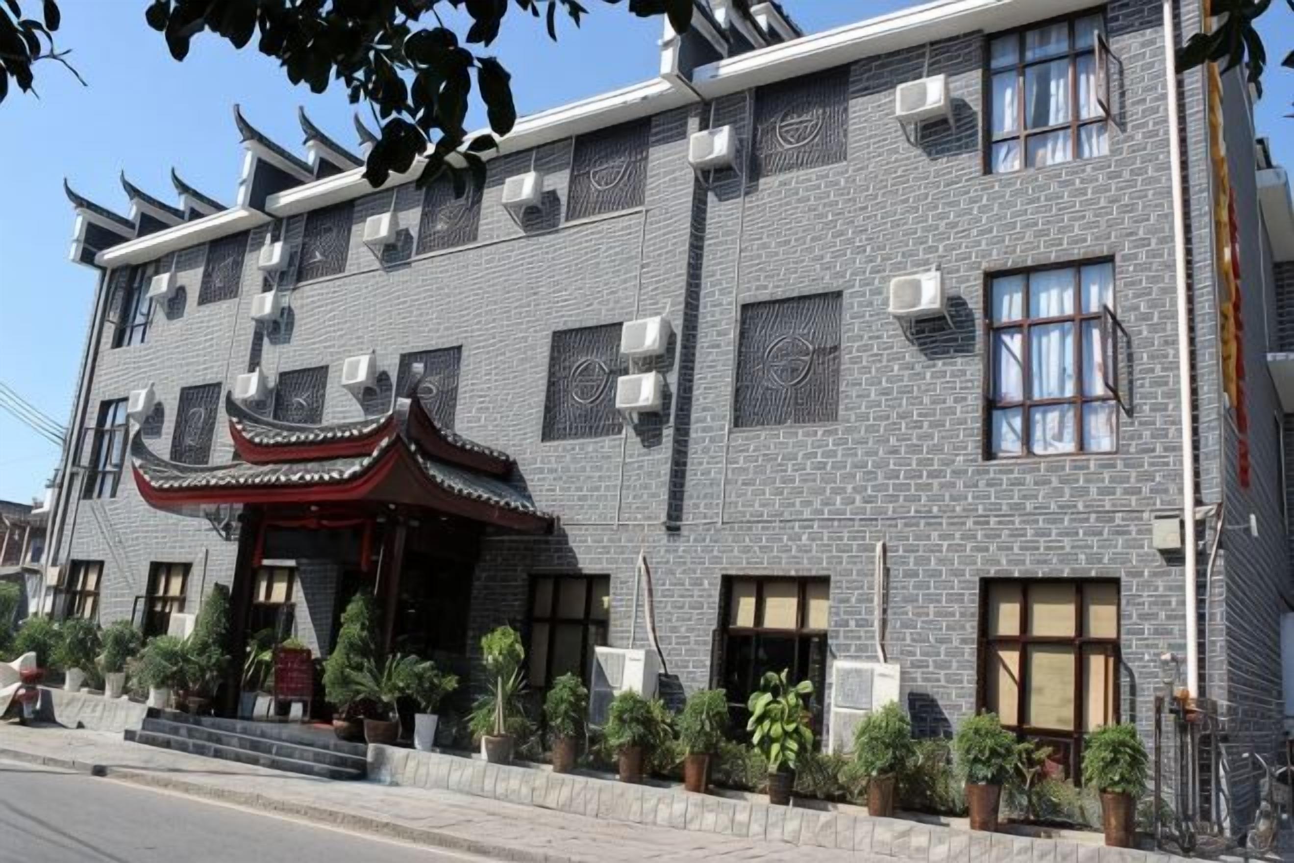 Un edificio de varios pisos con estilo arquitectónico tradicional, que presenta fachada de tejas, numerosas ventanas y una entrada decorativa con techo.