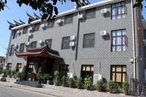 Un edificio de varios pisos con estilo arquitectónico tradicional, que presenta fachada de tejas, numerosas ventanas y una entrada decorativa con techo.