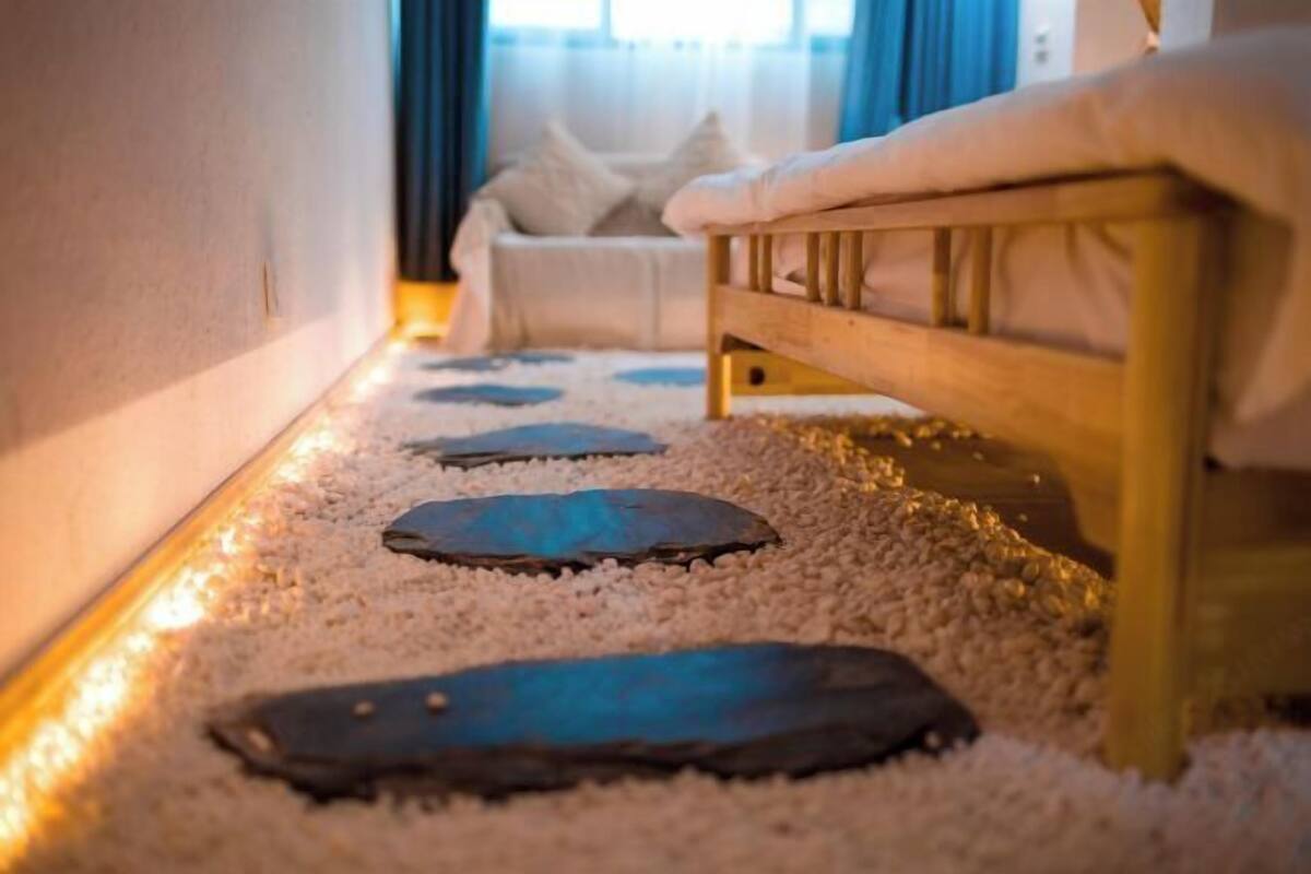 Una habitación con un banco de madera, un sofá blanco y un sendero con piedras.