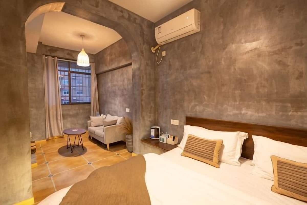 Una habitación con cama, sofá, una mesita y una ventana.