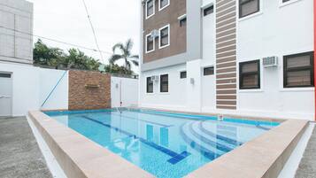 A swimming pool with a clear blue water feature, surrounded by a light-colored tiled deck.