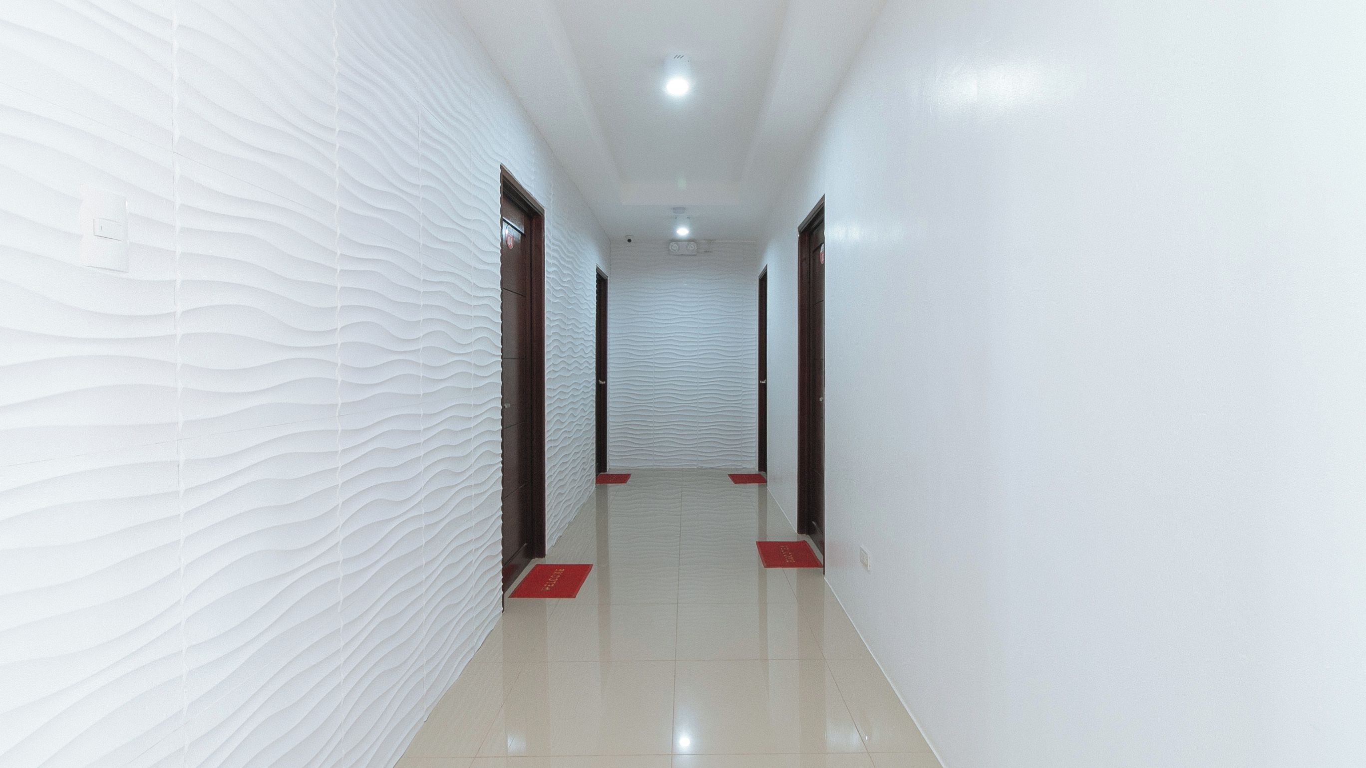 A corridor with textured walls, a tiled floor, and doors at the end.