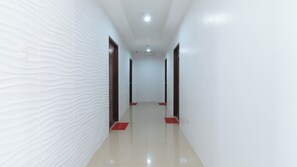 A corridor with textured walls, a tiled floor, and doors at the end. - Reddoorz Plus @ D'builders Poblacion - Bgc (Taguig)