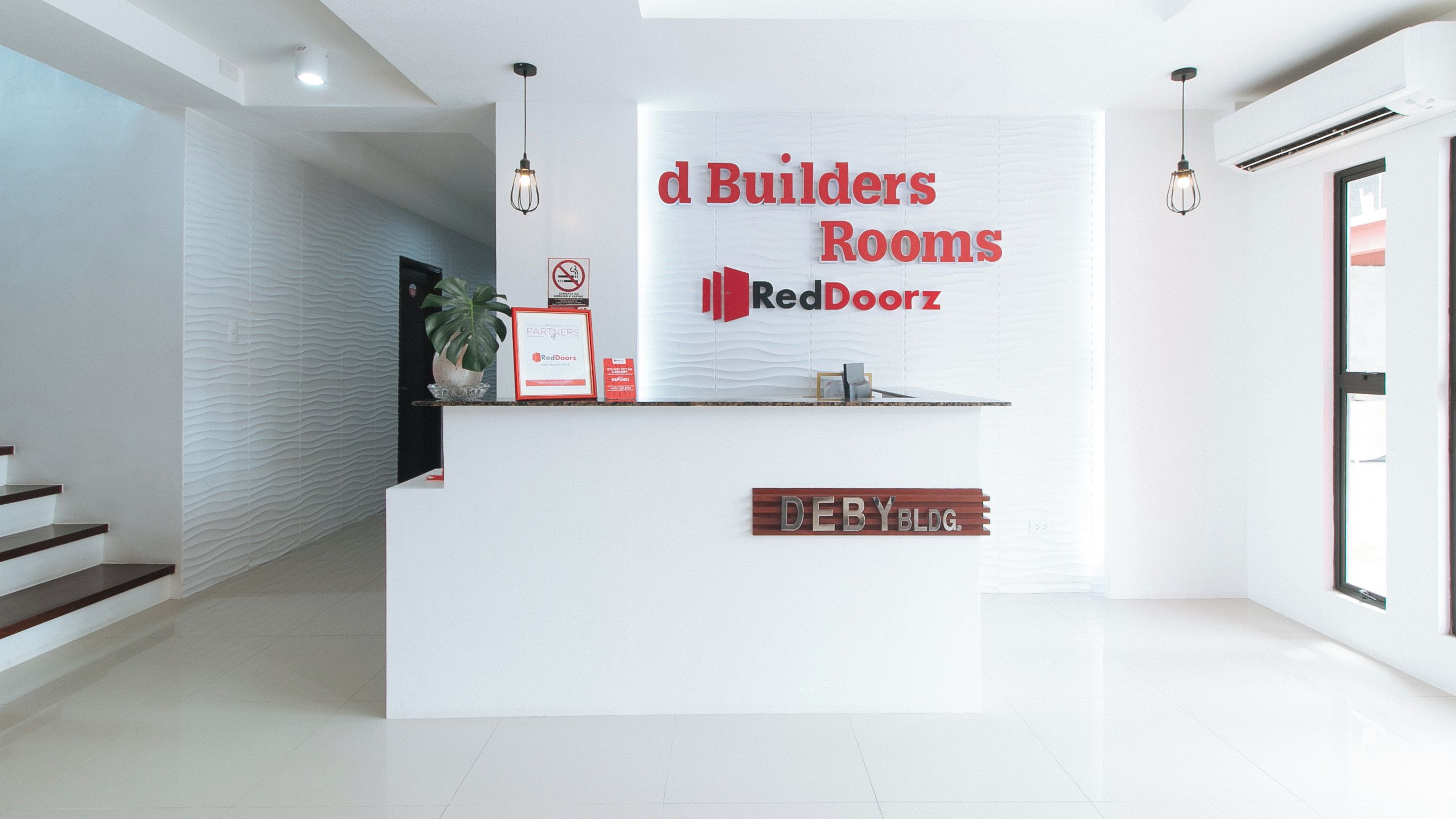 A reception desk with a sign for 'd Builders Rooms' and 'RedDoorz'.