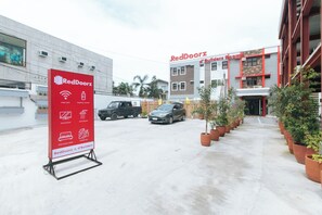 A RedDoorz building with a signboard listing amenities like free WiFi, mineral water, television, and a shower. - Reddoorz Plus @ D'builders Poblacion - Bgc (Taguig)