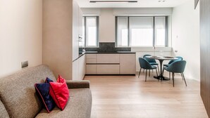 A modern apartment with a sofa, dining table, chairs, and a kitchen area. - Rubini 7 Suite Gold - MyHomeinComo (Como)