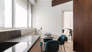 A modern kitchen with a large window, a dining area with a round table and chairs, and a wooden floor. - Rubini 7 Suite Gold - MyHomeinComo (Como)