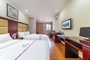 A hotel room with two beds, a desk with a computer, a television, and a large window.