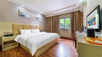 Une chambre d’hôtel avec un grand lit, un bureau avec un ordinateur et une télévision.