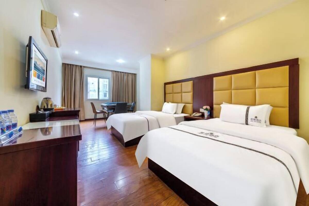 Habitación de hotel con dos camas, un escritorio, una silla y una ventana con cortinas.