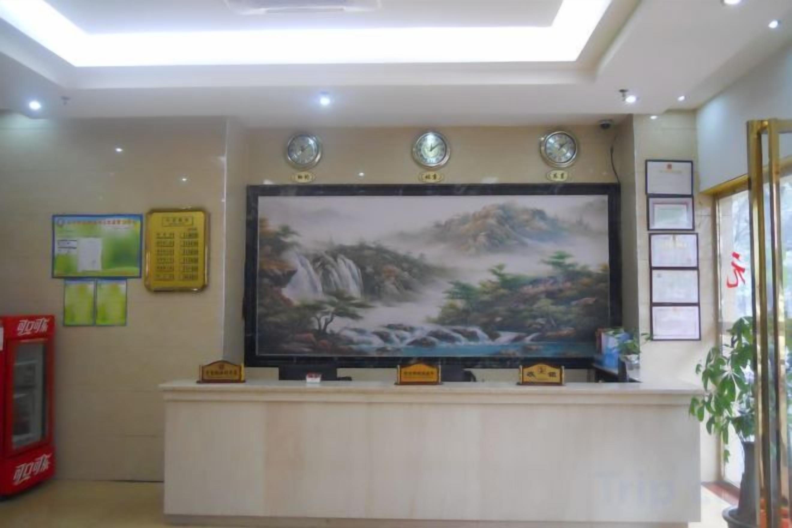 A reception area with a large painting, a clock, and a Coca-Cola refrigerator.