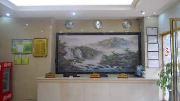 A reception area with a large painting, a clock, and a Coca-Cola refrigerator.
