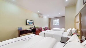 Habitación de hotel con dos camas, un escritorio con una silla, una mesita con botellas de agua y un cuadro en la pared.