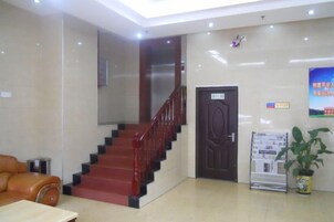 Un vestíbulo con una escalera, una recepción, una puerta y un cartel en la pared.