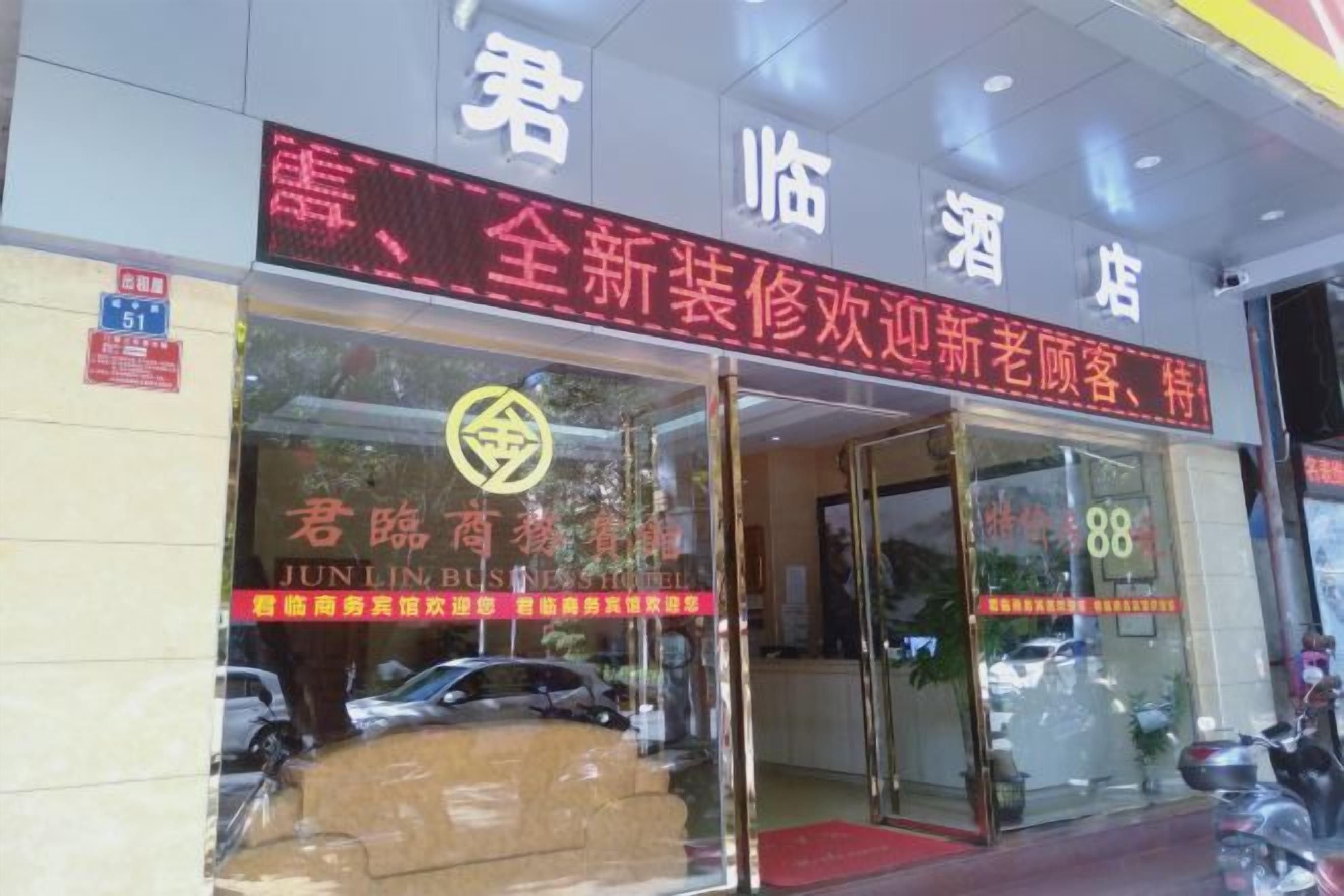 A hotel entrance with glass doors, a red carpet, and a sign with Chinese characters.