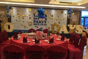 A round table set for a party with a banner in the background. - Jinkai Shengyucheng Hotel Sihui (Sihui)