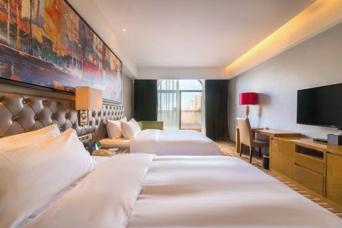 Une chambre d’hôtel avec un grand lit, un bureau, une télévision et un tableau au mur.