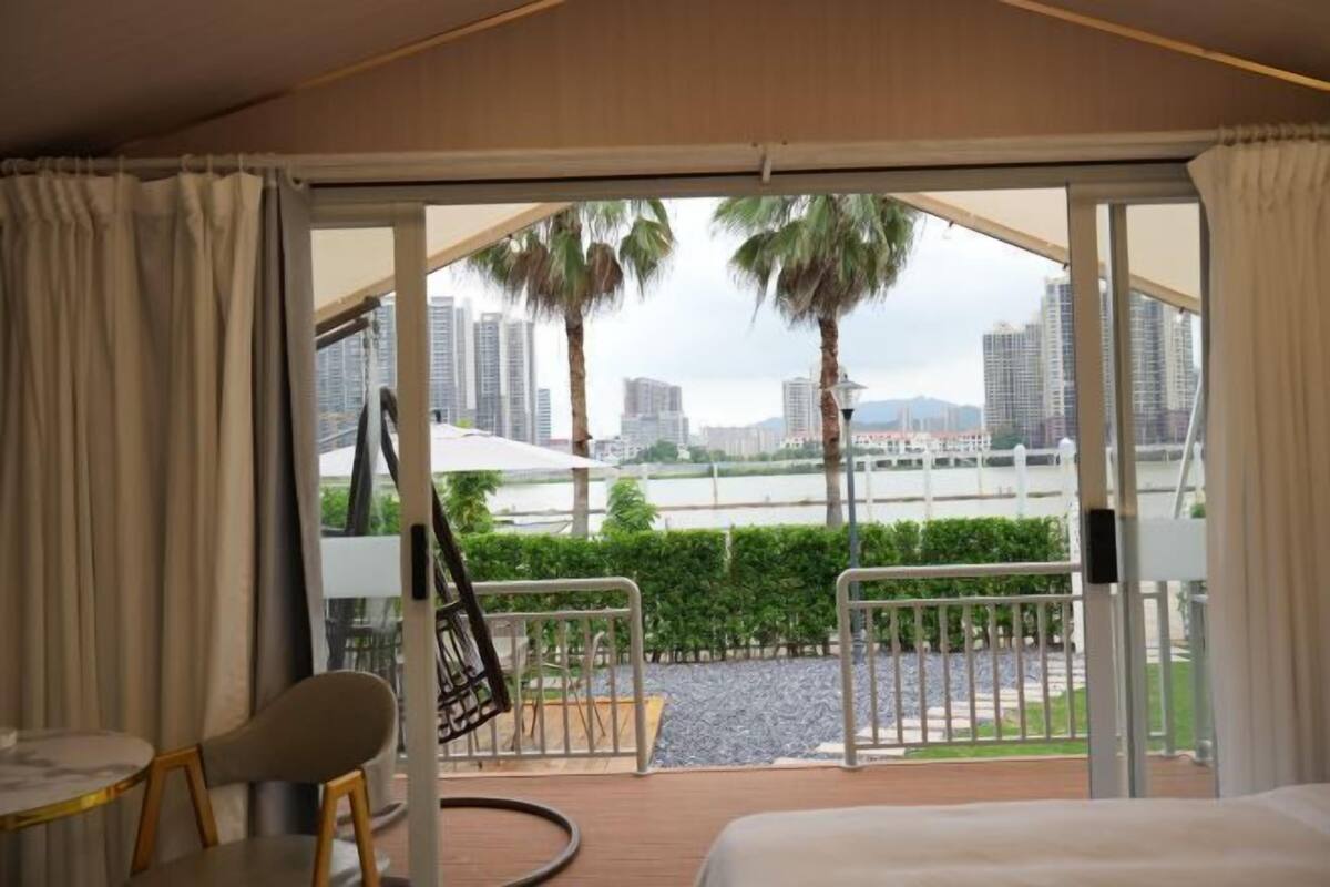Une chambre avec un lit, une chaise et une vue sur le paysage urbain, grâce à de grandes fenêtres.