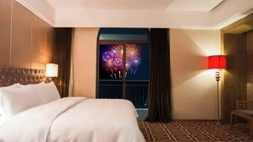 A hotel room with a bed, a nightstand, a lamp, a window with curtains, and a patterned floor.