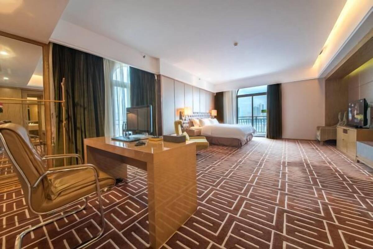 Une chambre d’hôtel équipée d’un lit, d’un bureau, d’une chaise, d’une télévision et offrant une vue sur la ville.