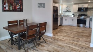 Een moderne keuken met roestvrijstalen apparatuur, een eethoek met een houten tafel en stoelen, en een keukeneiland.