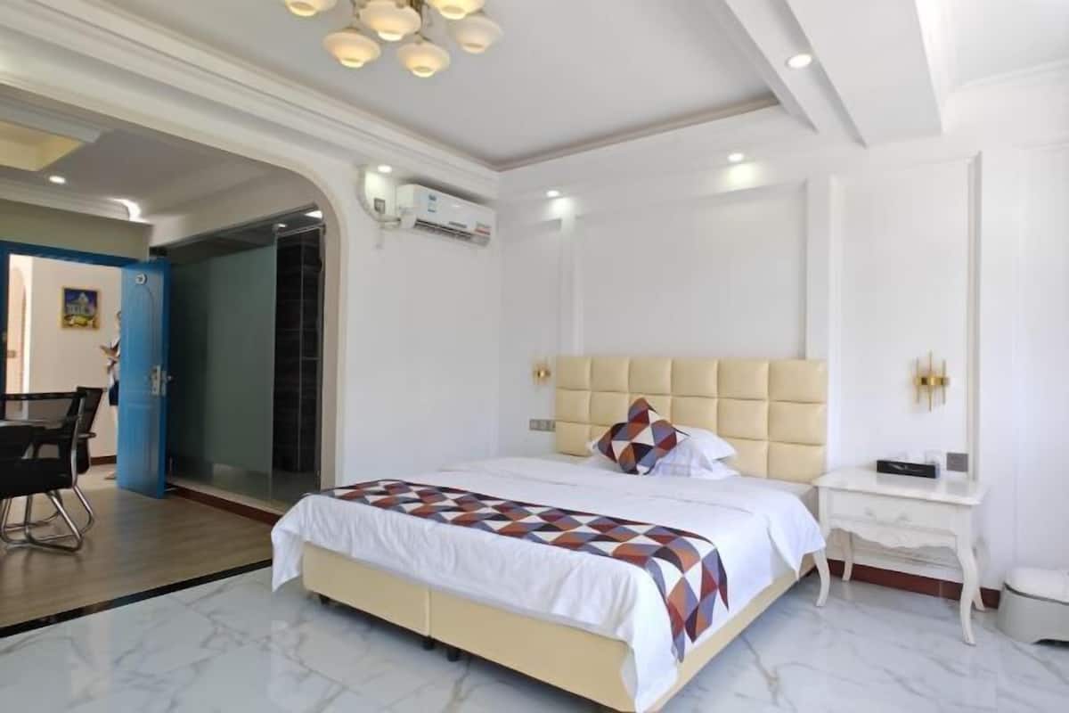 A hotel room with a bed, bedside table, and a desk with chairs.