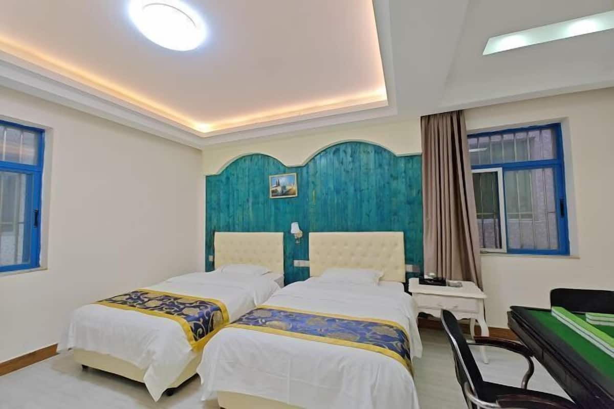 A hotel room with two beds, a desk, and a chair.