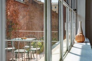 Ein Balkon mit Tisch und Stühlen, einer Ziegelwand und einer Vase auf dem Fensterbrett.