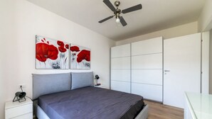 A bedroom with a bed, a ceiling fan, a nightstand, a lamp, and a wardrobe.