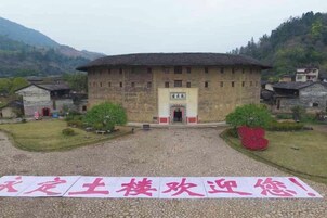 Un edificio tradicional con una entrada central, rodeado por un patio de grava y pequeños árboles.