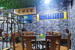 Un restaurante con paredes de ladrillo, mesas y sillas de madera. Hay carteles colgantes y una foto enmarcada en la pared.