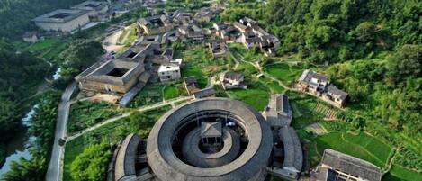 Un bâtiment circulaire entouré de constructions traditionnelles, avec une rivière et de la verdure en arrière-plan.