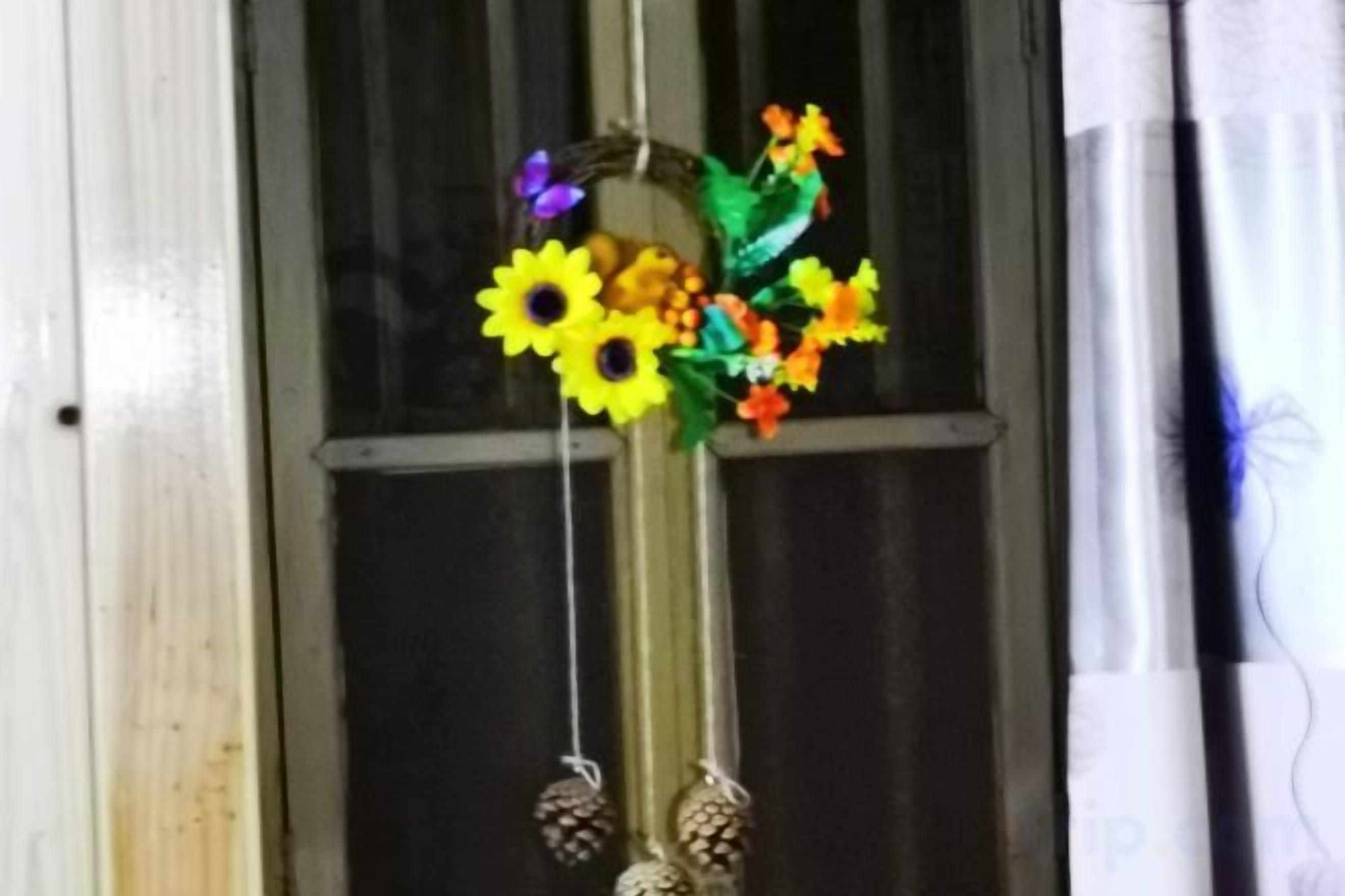 Una ventana con un adorno colgante de girasoles y piñas.
