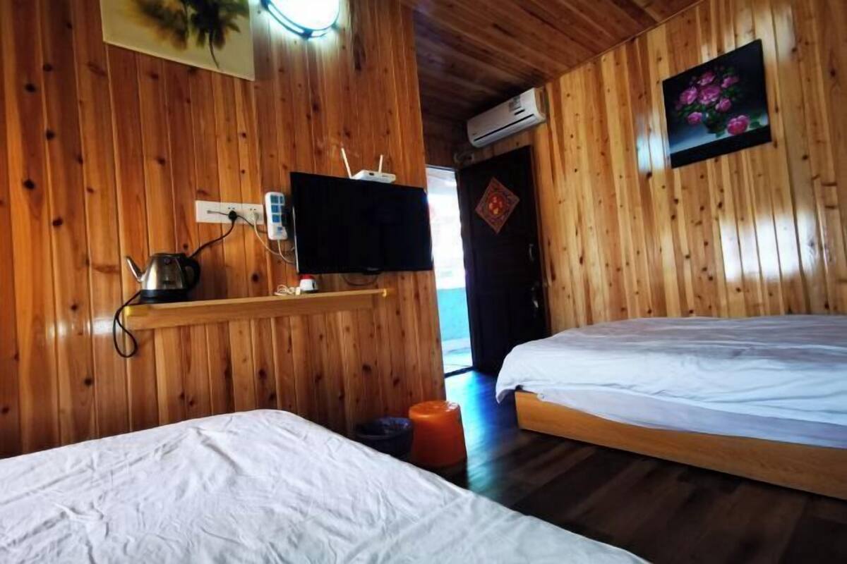 Ein Zimmer mit Holzboden, zwei Betten, einem Fernseher und einer Steckdose.