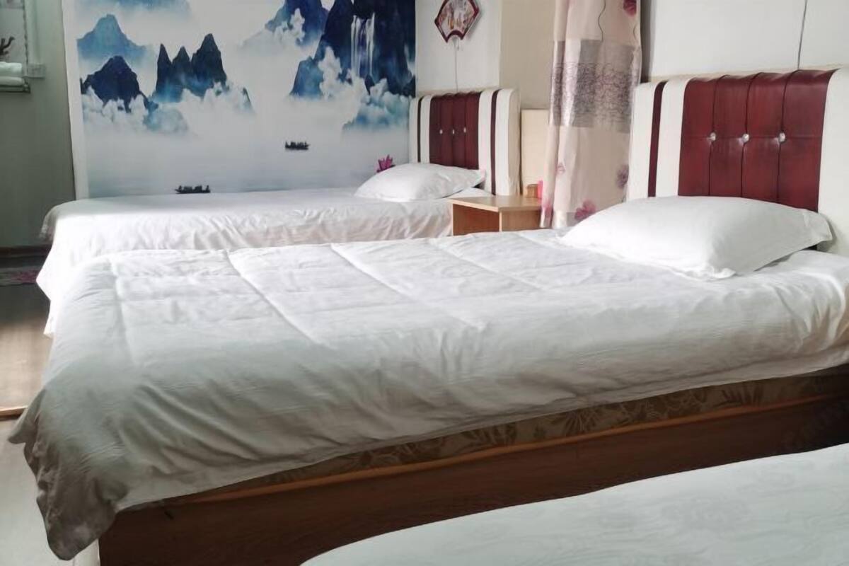 Ein Hotelzimmer mit zwei Betten, einem hölzernen Kopfteil, einem Nachttisch und einem Wandbild.