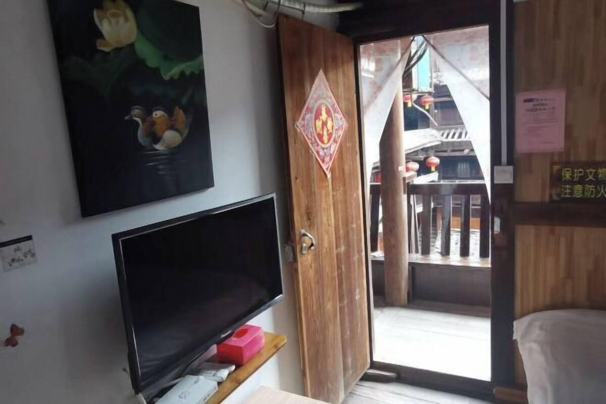 Ein Zimmer mit Holztür, einem Fernseher und einem Erlenzbild.