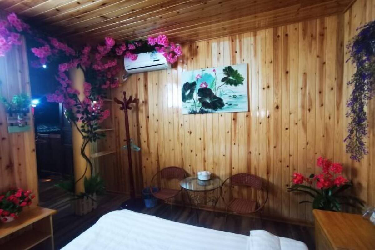 Ein Zimmer mit Holzboden, einem Bett, einem kleinen Tisch mit Stühlen und einem Bild an der Wand.