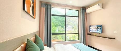 Una habitación de hotel con cama, televisión y ventana con cortinas.