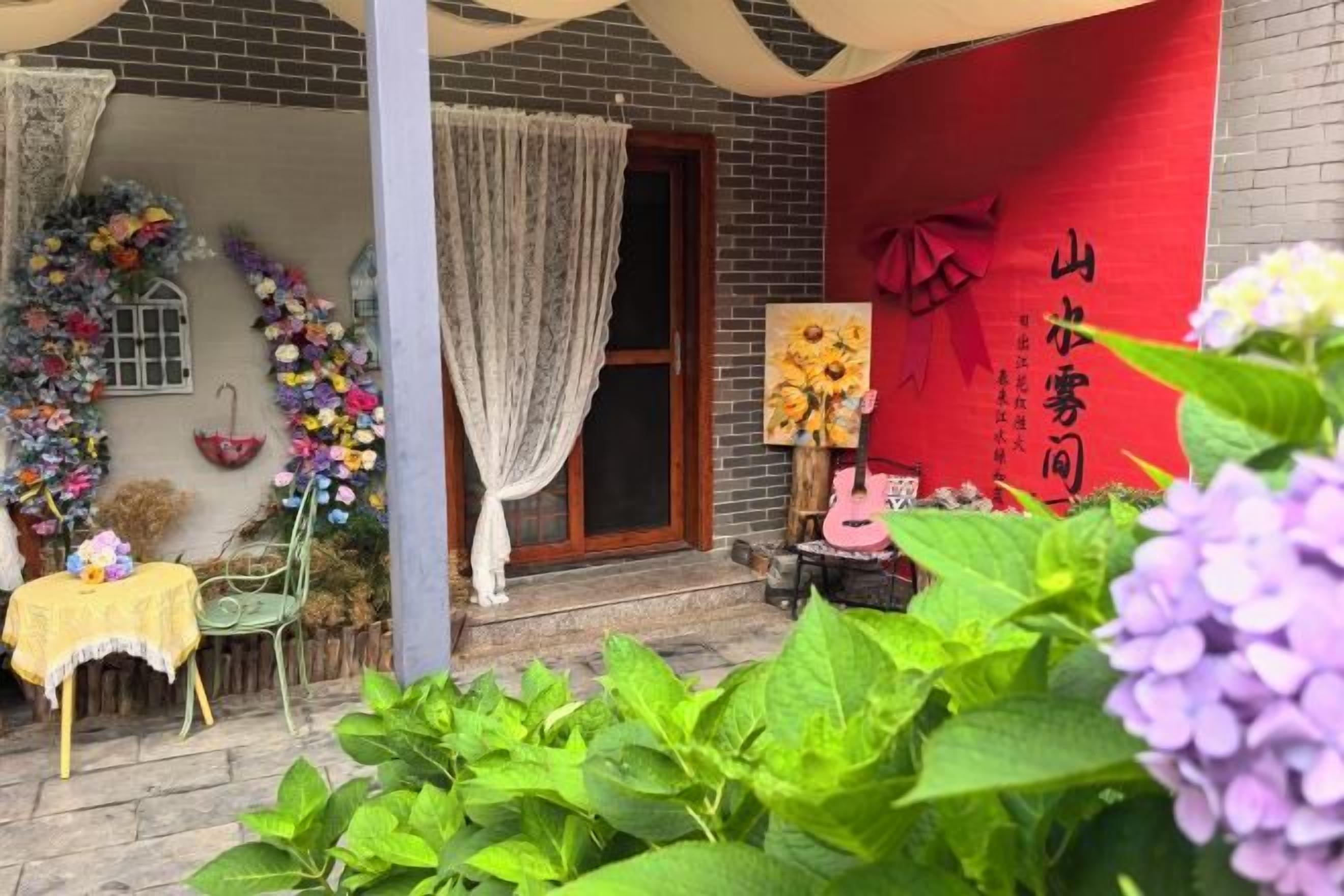 A traditional Chinese building with a red wall, a wooden door, and a small table with a yellow tablecloth.