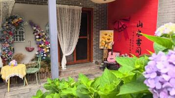 A traditional Chinese building with a red wall, a wooden door, and a small table with a yellow tablecloth.