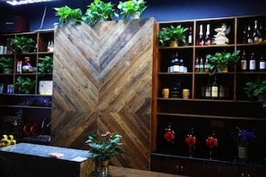 A bar area with a wooden chevron wall, shelves with bottles, and potted plants. - Shanshui Wujian lnn (Zixing)