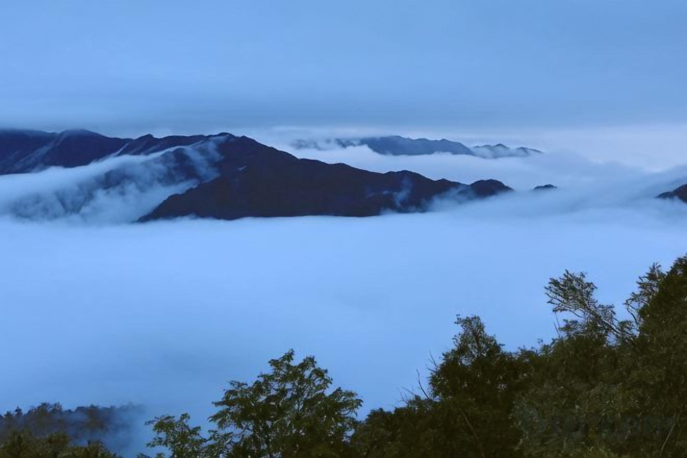 Paisaje montañoso con nubes a la base, lo que sugiere una gran altitud.