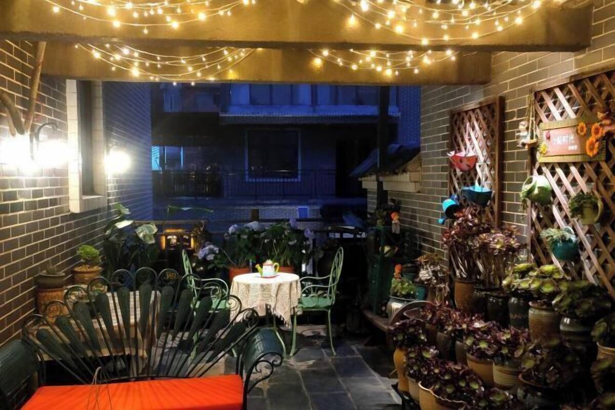 Ein Patio mit Lichterkette, einem Tisch mit Stühlen und Kübelpflanzen.