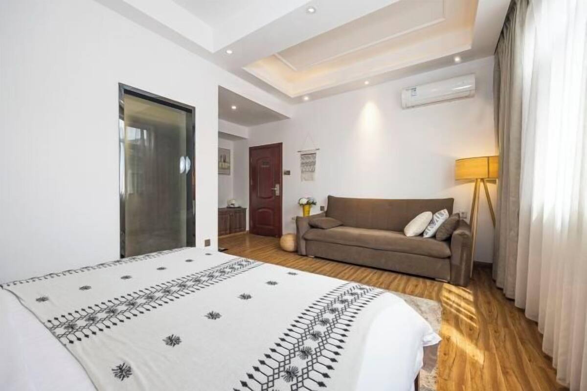 Ein Schlafzimmer mit einem Bett, einem Sofa, einer Lampe und einer Tür.