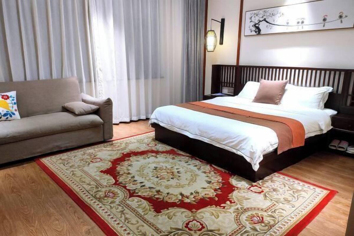 Ein Hotelzimmer mit einem Bett, einer Couch, einem Teppich und einem Wandbild.