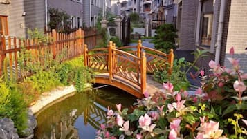 Un canal estrecho con un puente de madera, rodeado de edificios de ladrillo y abundante vegetación.